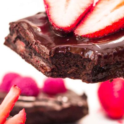 Closeup on the Double Chocolate Brownies with one bite missing and two halves of a strawberry on top