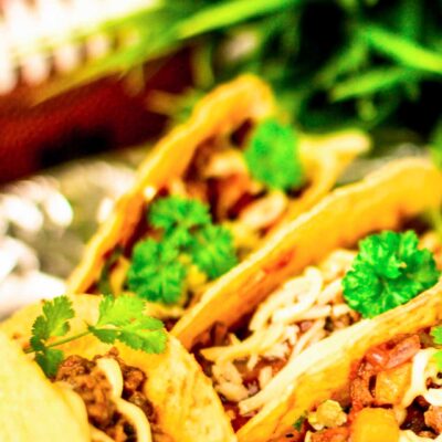 Four Tailgate Tacos with a football and a pot full of green grass blurred in the background
