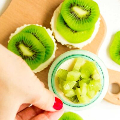 Grabbing a small jar full of the mouthwatering Kiwifruit Cheesecake recipe with a couple of cupcake bites laying right next to the glass jar