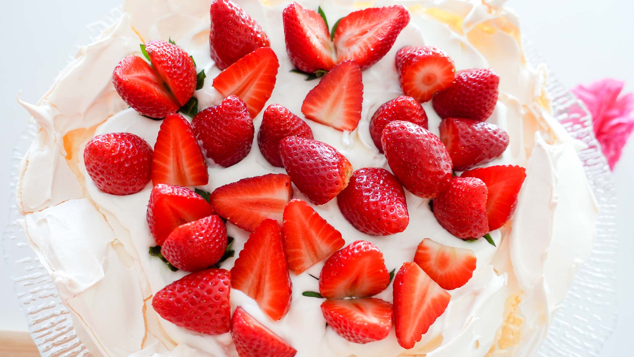 A photo of decorated Strawberry Pavlova on a glass plate