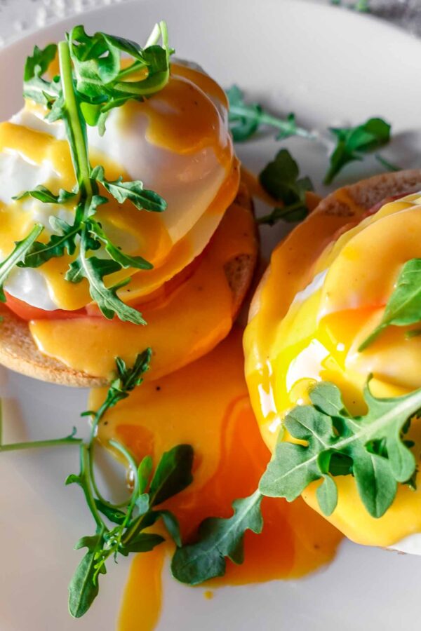 Caprese Eggs Benedict on a plate with arugula and running egg