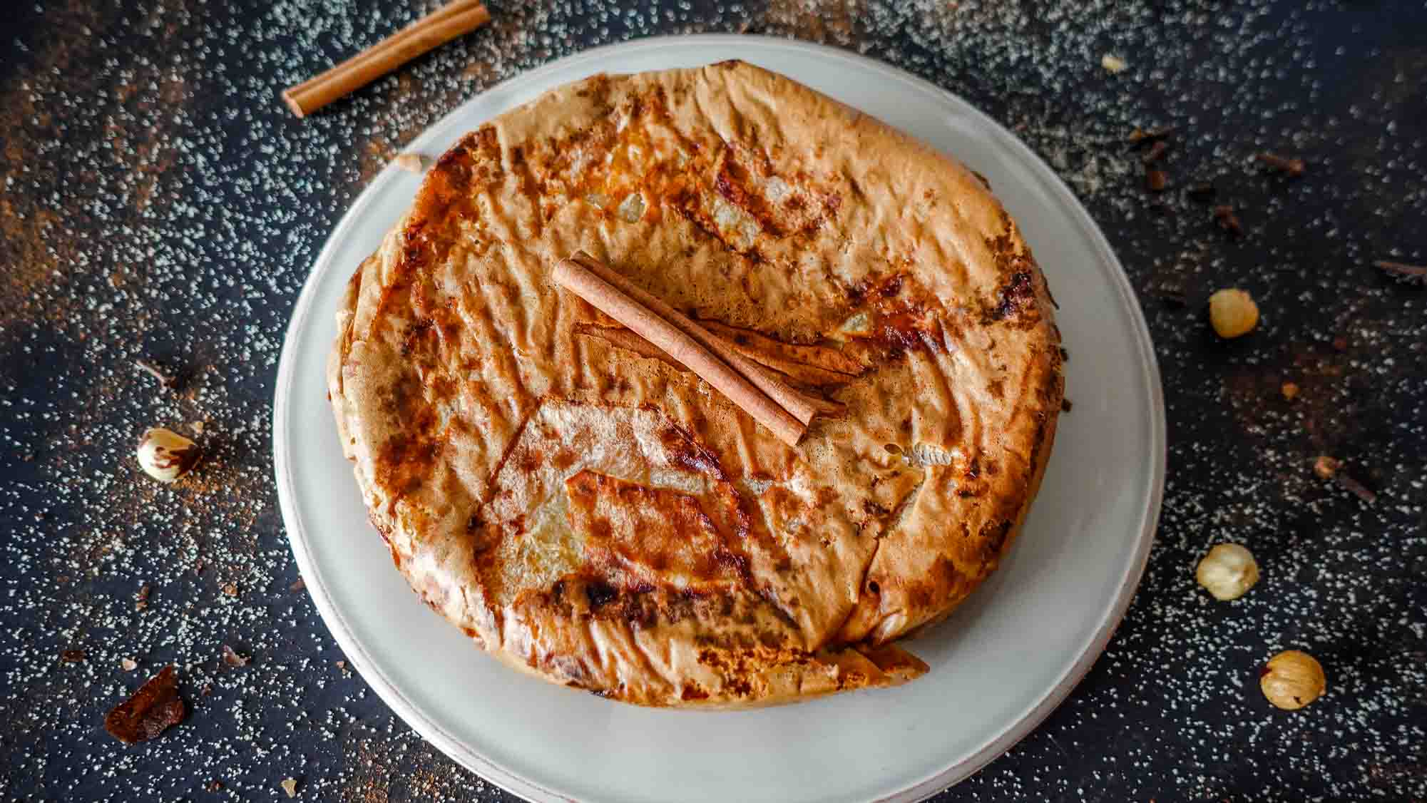 Apple Cinnamon cake on a plate with a cinnamon stick on top.