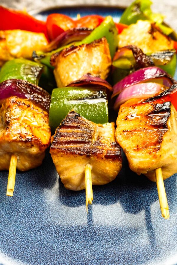 Mouthwatering salmon kabobs on blue plate.