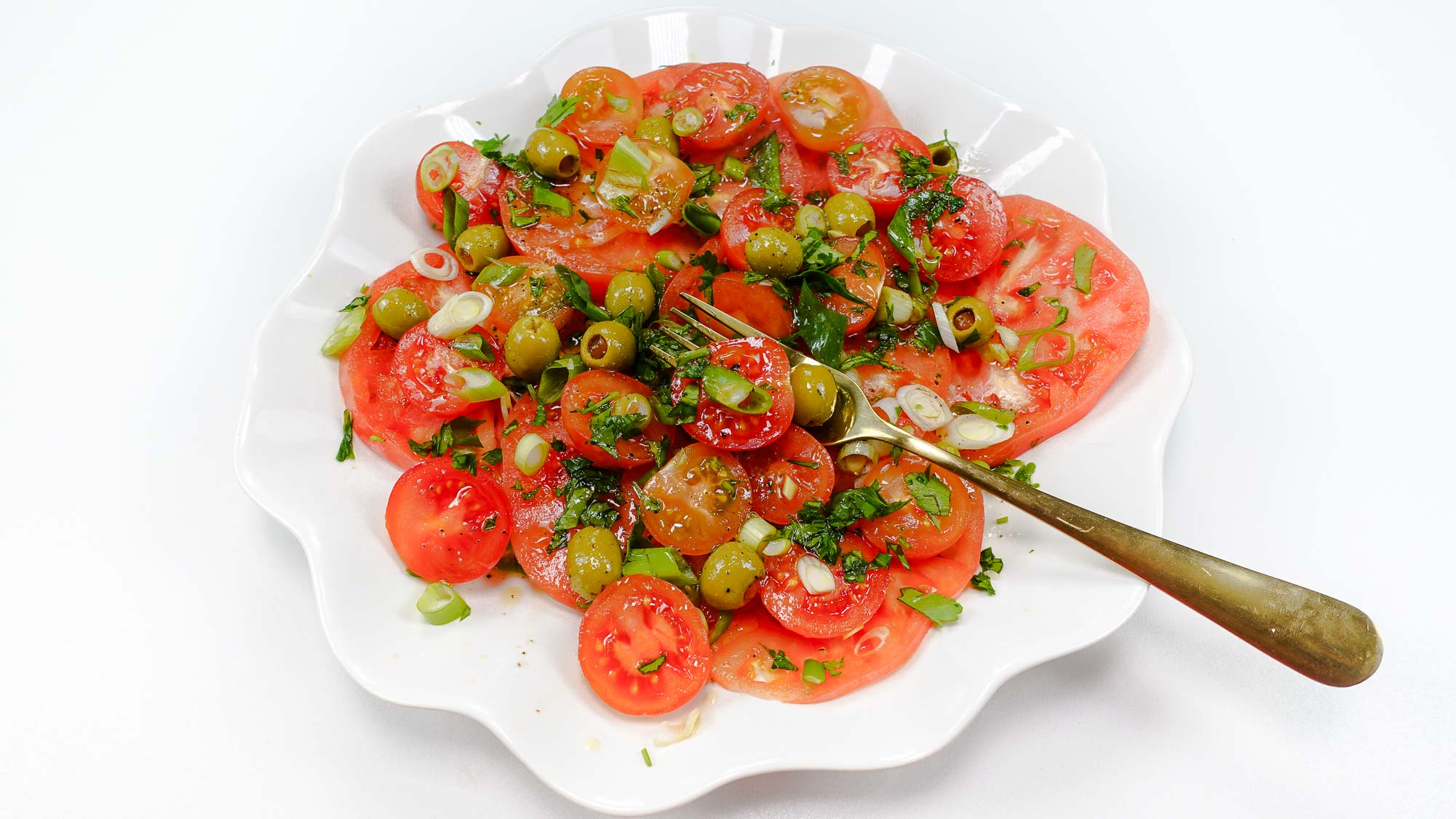 Tomato Salad with olives on a white plate.