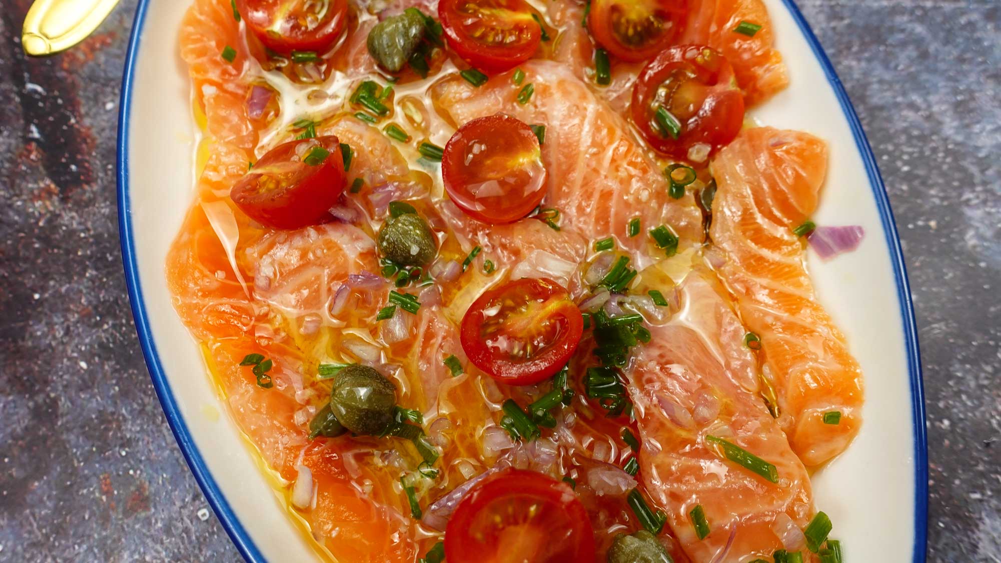 A closeup of delicious Salmon Carpaccio on a plate with a small spoon.