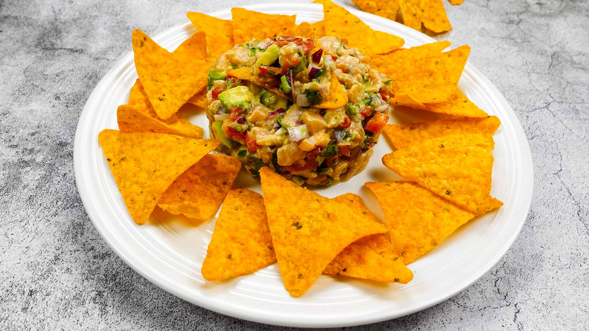 Spicy Salmon Tartare with Corn Chips on a white plate.