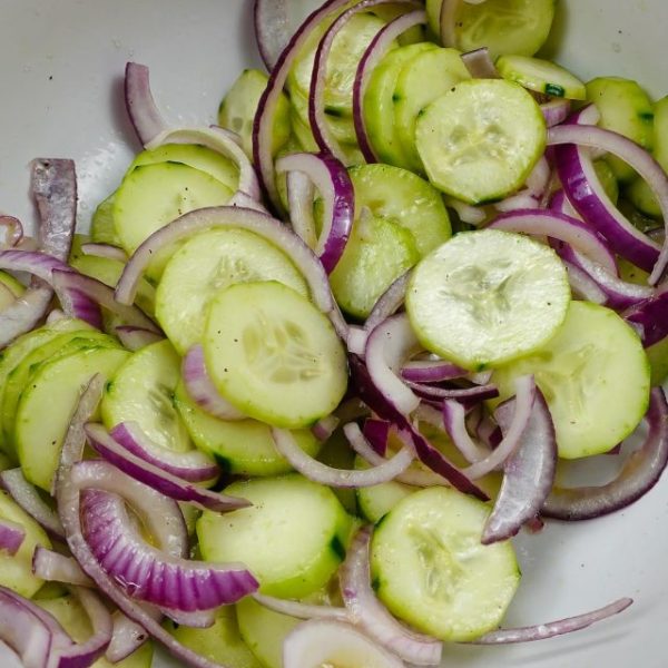 A closeup of Cucumber Red Onion Salad Recipe in a big white bowl.