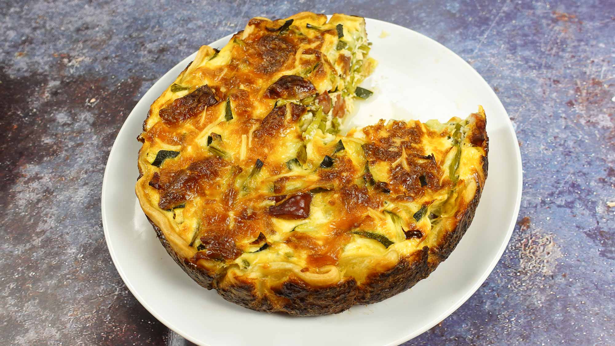 Well shaped round quiche with veggies in soft golden dough.