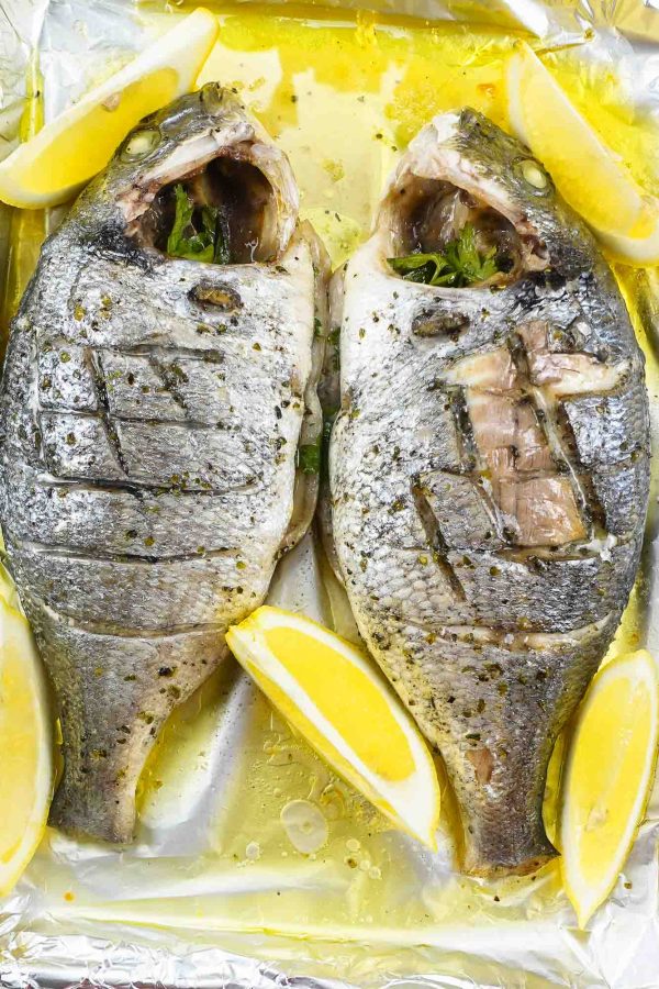 Foil baked Sea Bream with fresh lemon slices on a tray.