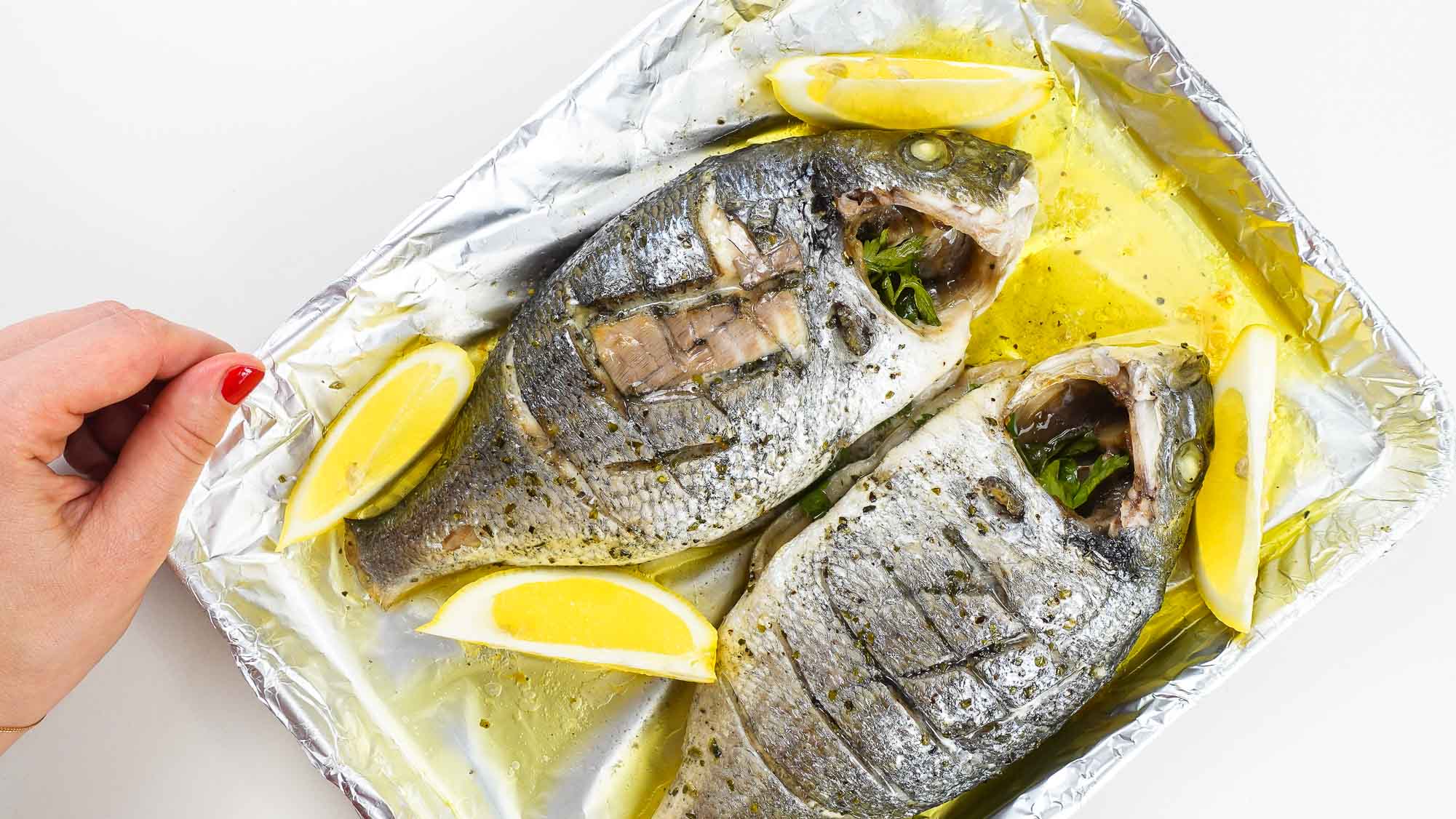Delicious Foil baked Sea Bream with fresh lemon slices on a tray.