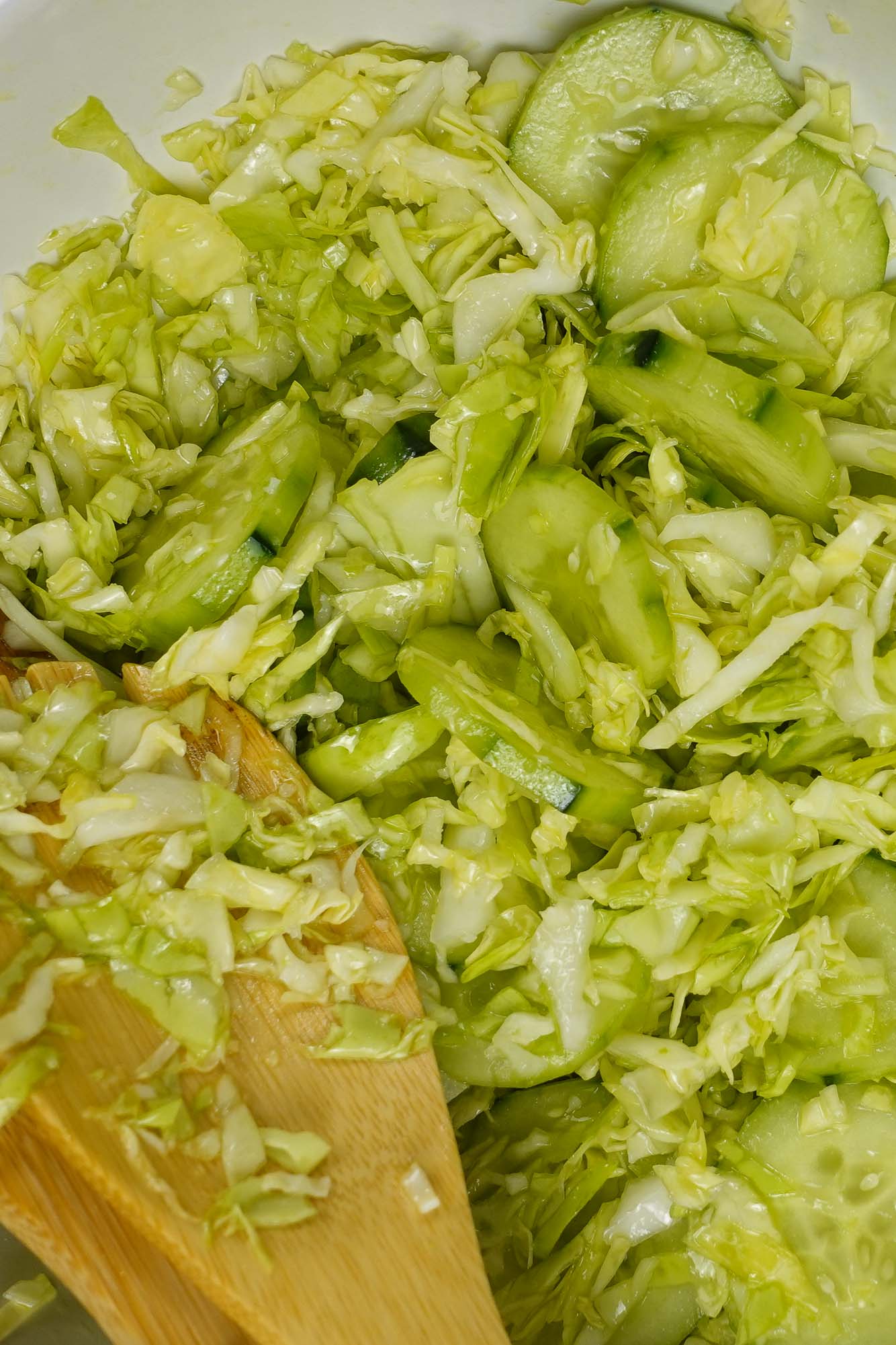 A closeup of Cabbage Cucumber Salad with a spoon and a fork.