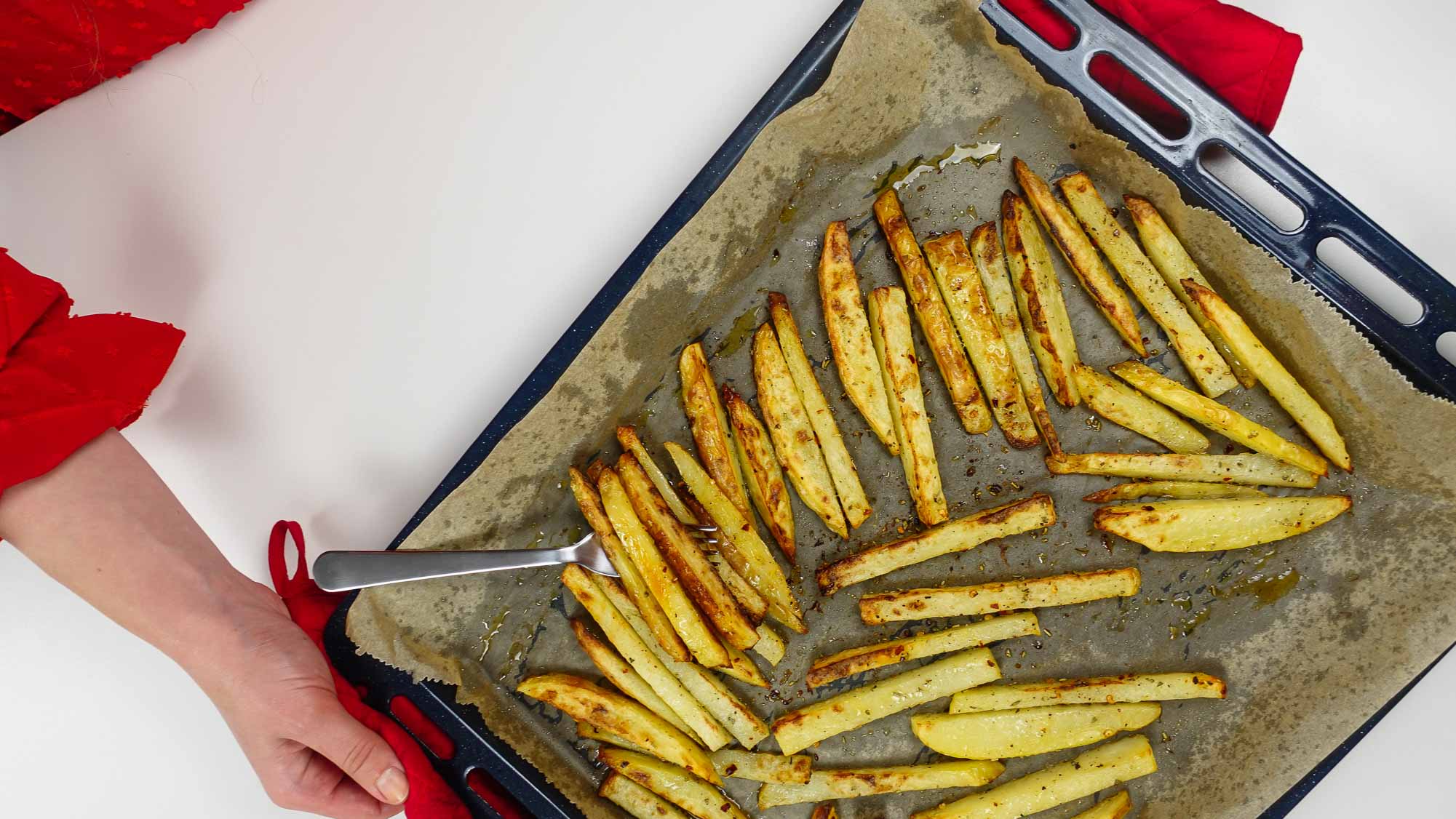 Holding a tray with potatoes just cooked from the oven.